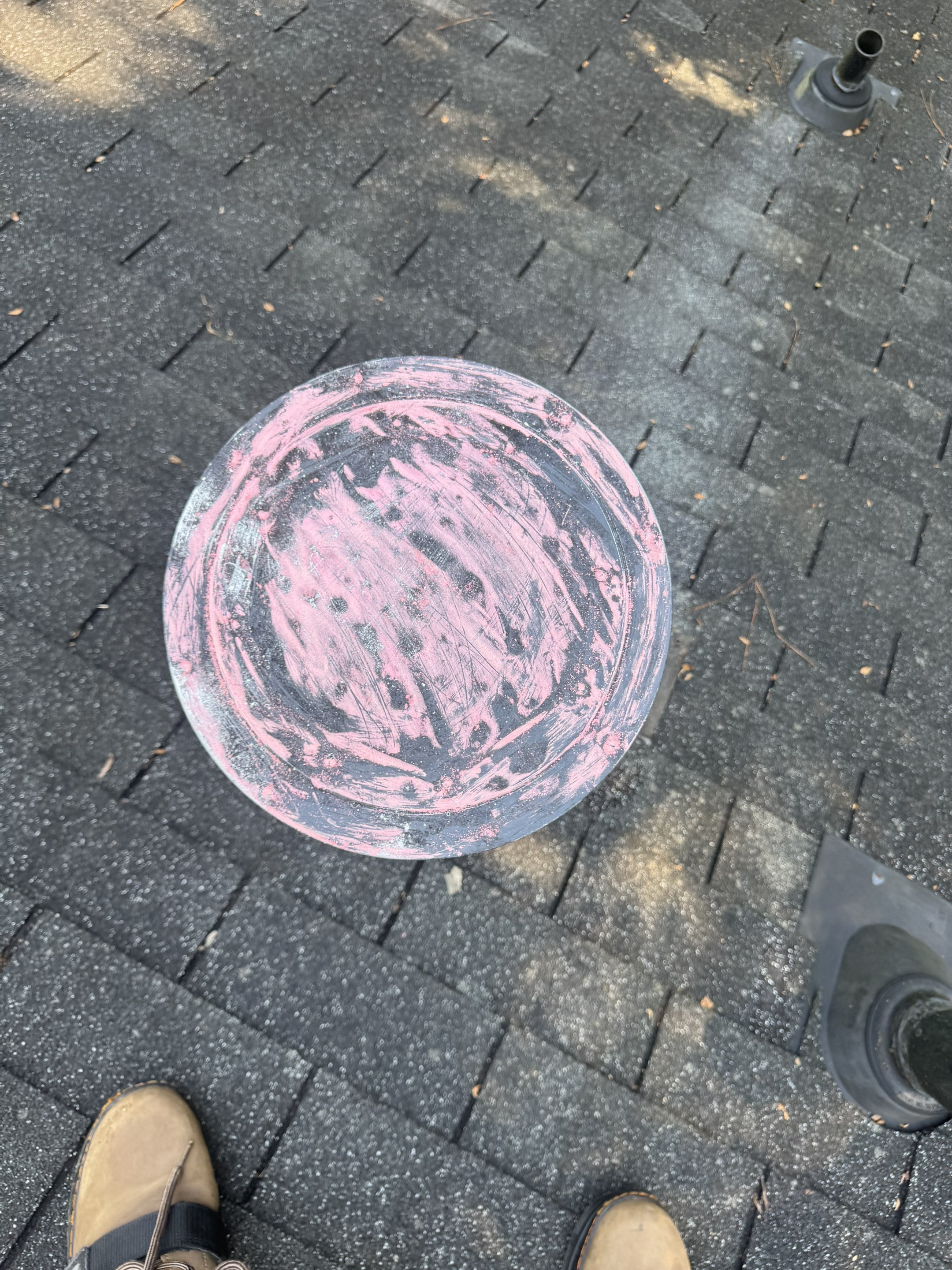Close-up of a roof vent boot with pink chalk damage markings. Mosaic Roofing inspector boot visible. Documentation work for insurance claim.