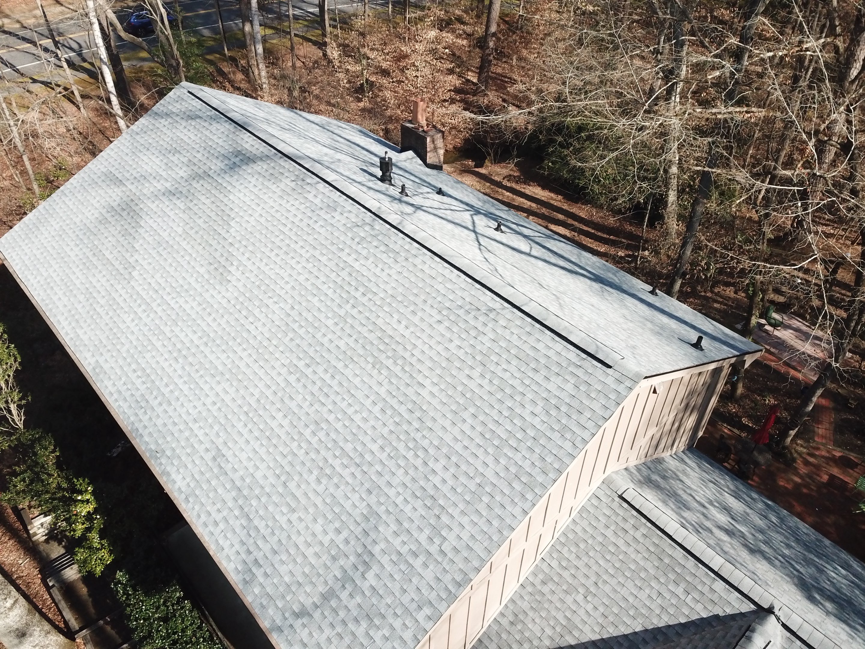 Aerial drone view of a completed Mosaic Roofing replacement at the Lawson Herron home in Roswell GA — clean light gray architectural shingles, full roof view from above.